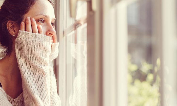 Young woman staring out window TURNING-TRAUMA-TO-HEALING