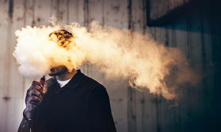 man surrounded by smoke from electronic cigarette